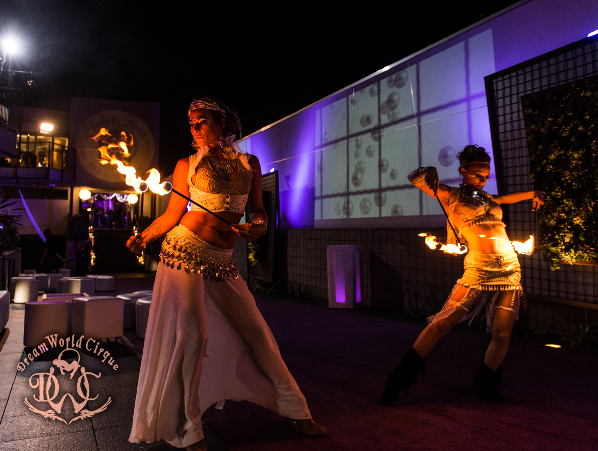 two beautiful fire dancers dressed in all white perform fire eating and transfers as guests arrive at a luxurious event